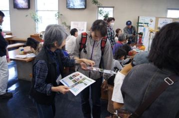 コーナーの運営に関しては，植物園のボランティアの方々に大変お世話になりました。来場者にカワラケツメイのお茶の楽しみ方を説明するボランティアさん。