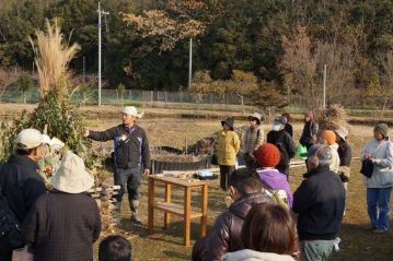 どんど焼きに使用している植物の説明中。本来は竹が破裂する音で、魔を祓うと言われますが、ちょっと危ないので、節に穴を開けて破裂しないようにして、その代わりに燃やすとパチパチ音がする、トウネズミモチの葉を使ってあります。