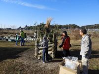 14日：植物園を楽しむ会82（とんど焼きでむかしを楽しむ）開会前、とんどのやぐらに正月飾りを置く参加者。