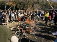 13日：植物園を楽しむ会94「寒中をとんど焼きで楽しむ」（とんどの火でメダケに挟んだお餅を焼く参加者）