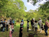 この日も開会の8時に既に30℃を超える暑い日でした。 講師の守安先生のお話は少しだけ涼しい木陰で。